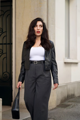 a lady wears a black leather jacket with white t-shirt and gray pants